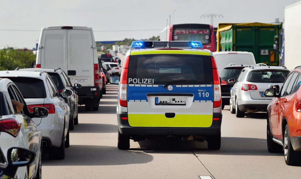 Ein Polizeiauto fährt durch eine Rettungsgasse zu einer Unfallstelle auf der Autobahn.