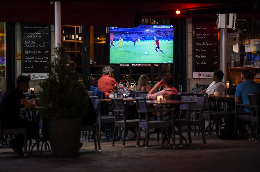 In Außenbereich eines Restaurants schauen Gäste ein EM-Gruppenspiel.