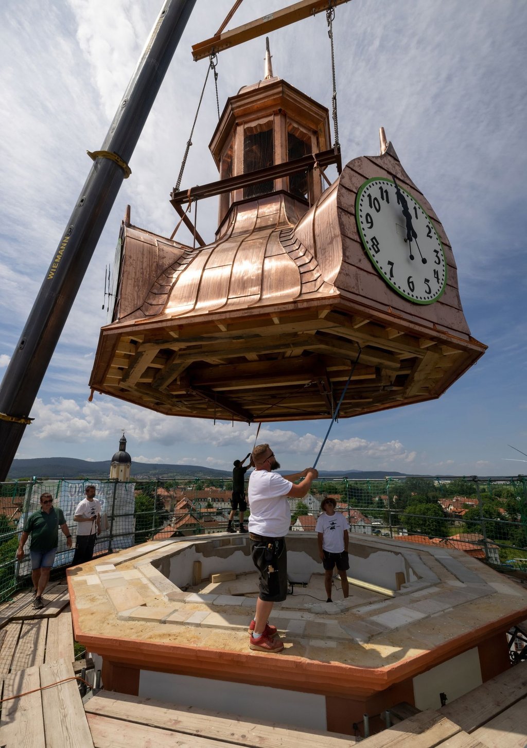 Mit einem Kran wird die sanierte Turmhaube von Schloss Ehrenstein aufgesetzt.