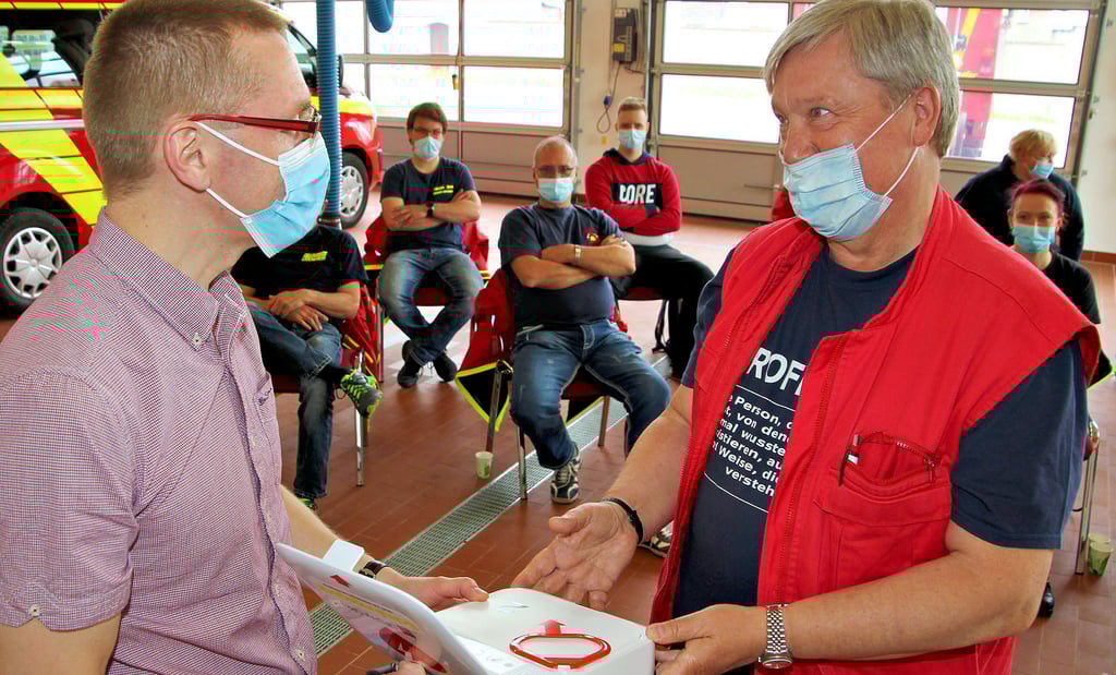 Matthias Röder (v.l.) und Prof. Gerd Meißner erklären den Löschkräften die Technik für die erste Hilfe.