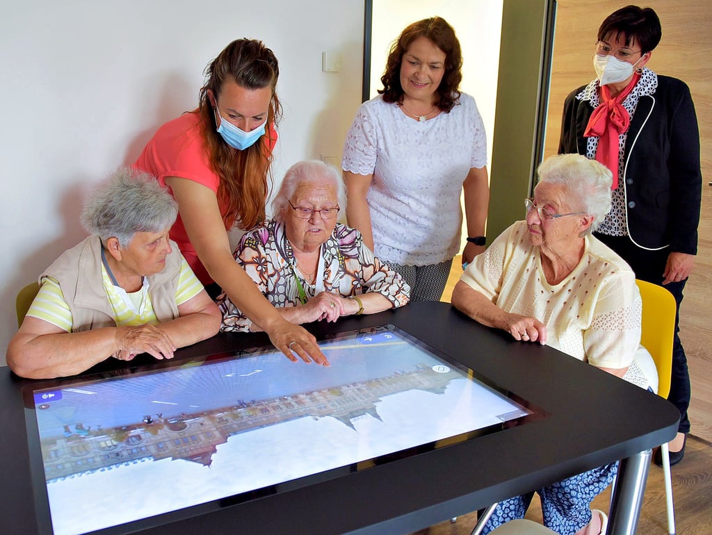 Die Seniorinnen Helga Meinicke, Marga Schmidt und Christa Wendler (v.l.) probieren den digitalen Tisch aus. Pflegedienstleiterin Stefanie Barthel, Awo-Geschäftsführerin Ute Düsterhöft und Annett Görlich (v.l.), Vorstandsmitglied der Sparkasse Mansfeld-Südharz, schauen zu.