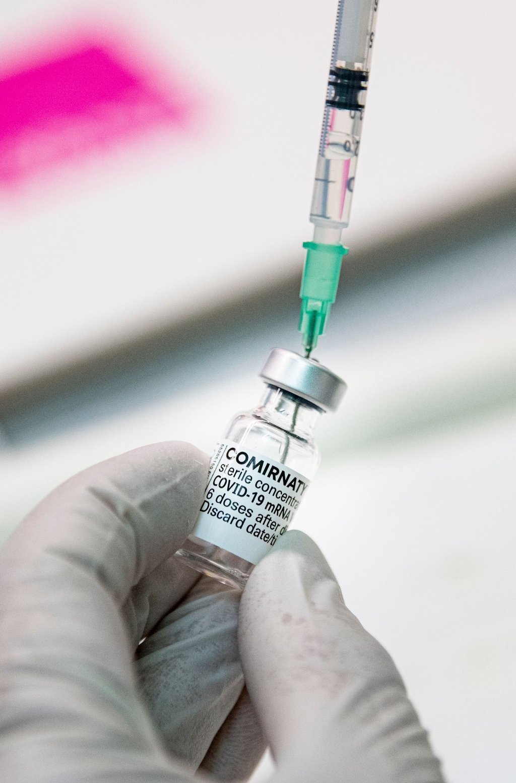 Ein Arzt zieht den Corona-Impfstoff Comirnaty von Biontech/Pfizer in eine Spritze.