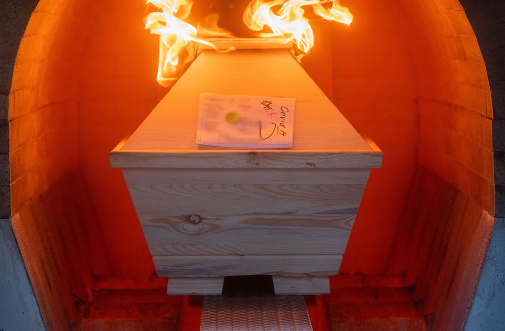 Ein Verstorbener in einem Sarg mit Aufschrift "Covid-19" wird im Krematorium in einem Ofen eingeäschert.