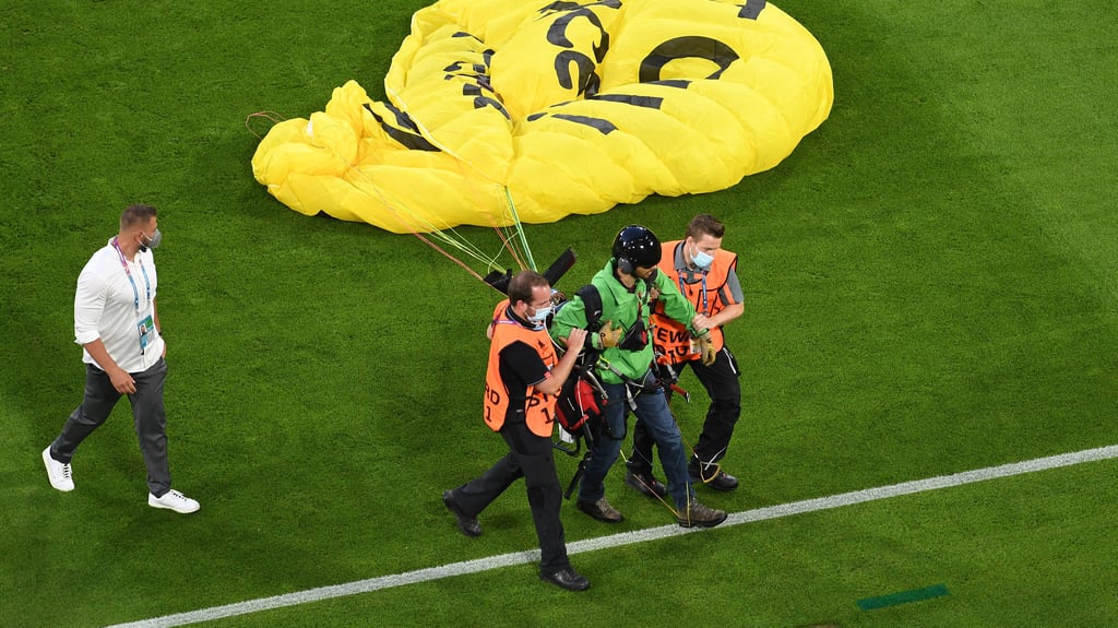 Der Motorschirm-Pilot wird nach seiner Landung auf dem Rasen des Münchner EM-Stadions abgeführt.