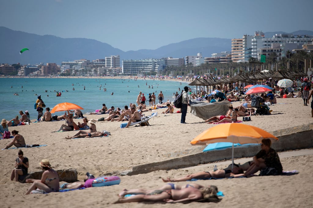 Touristen genießen die Sonne an einem Strand auf der spanischen Insel Mallorca. Landesweit startet die Sommertourismus-Saison mit coronabedingten Einschränkungen.