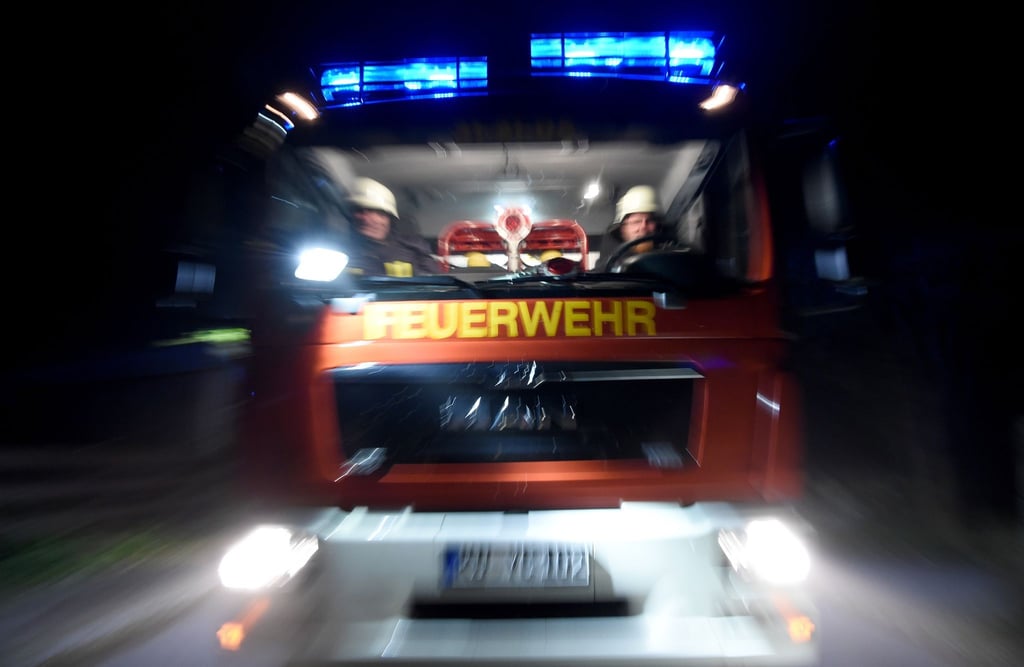 Ein Löschfahrzeug fährt mit Blaulicht über eine Straße.