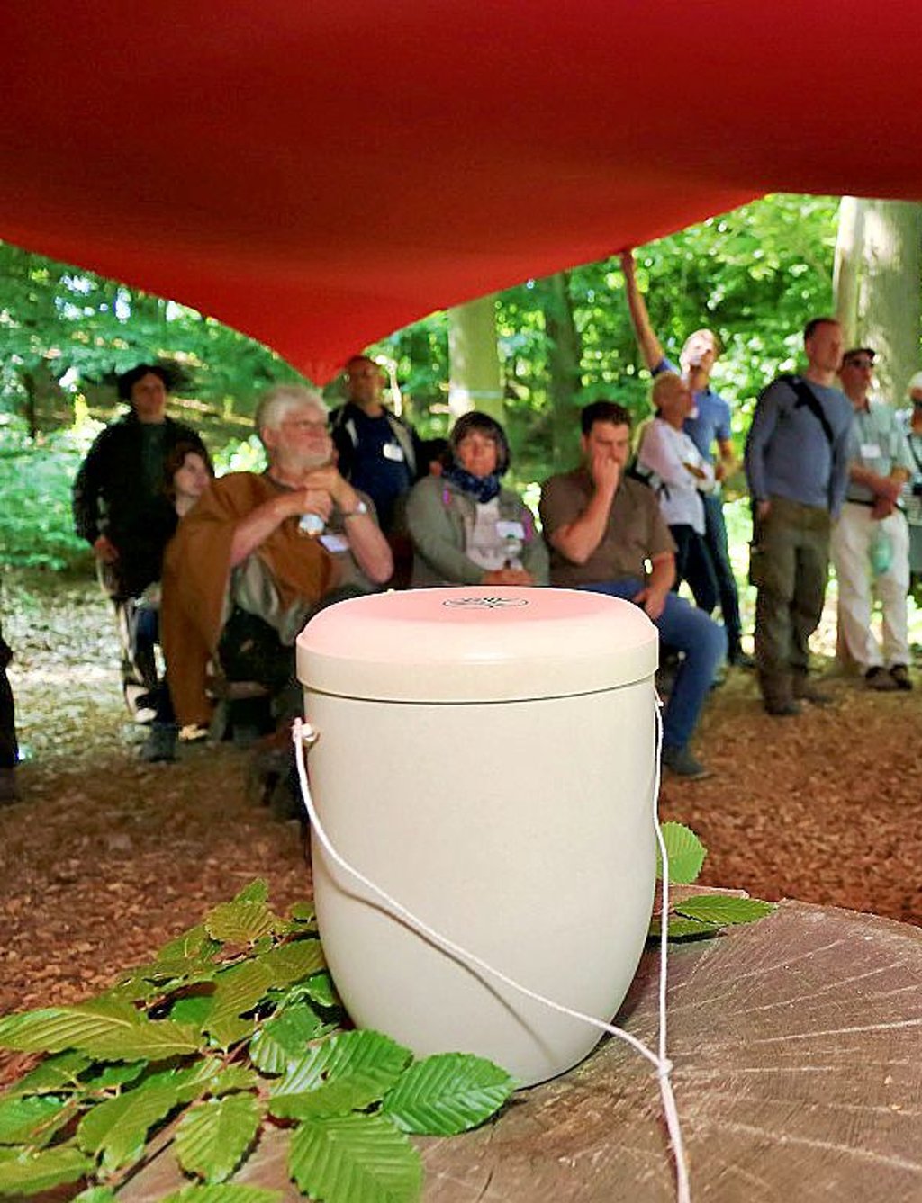 Besucher bei der Friedwaldbegehung unterm Sonnensegel.