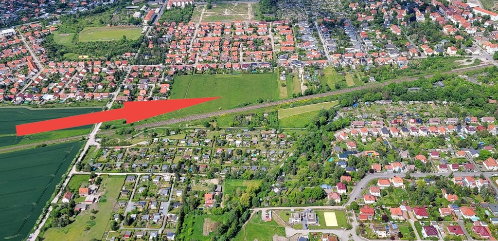 Blick auf den Südwesten Halberstadts. Zwischen Bahnlinie (in der Bildmitte schräg nach rechts oben verlaufend) und Beethovenstraße plant die Stadt ein Eigenheimgebiet (roter Pfeil) mit der Möglichkeit zur Pferdehaltung. Weiter südlich sind Kleingartensparten zu sehen und das Sonntagsfeld (rechts unten).