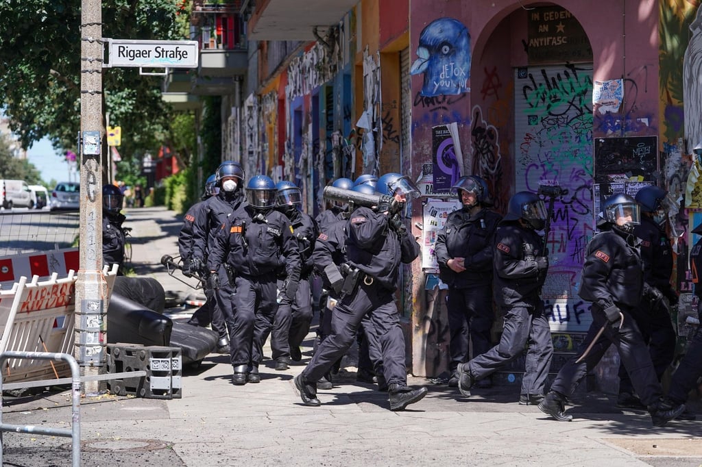 Polizisten gehen mit einem Rammbock vorbei an einer Barrikade in die Rigaer Straße.