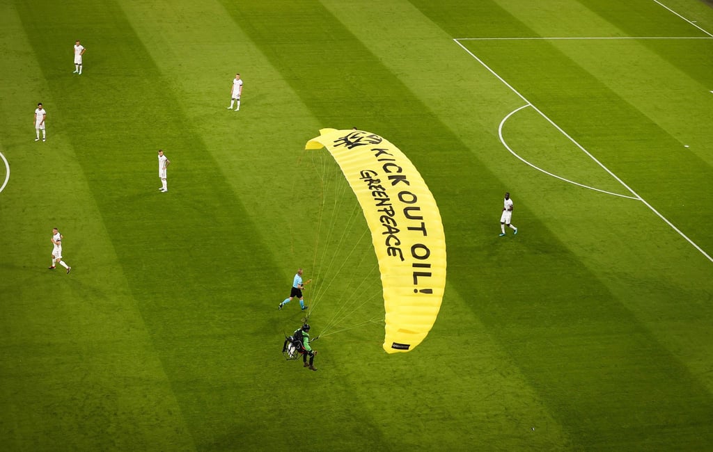 Ein Greenpeace-Aktivist landet mit einem Motorschirm-Flieger bei einer Protestaktion auf dem Spielfeld.