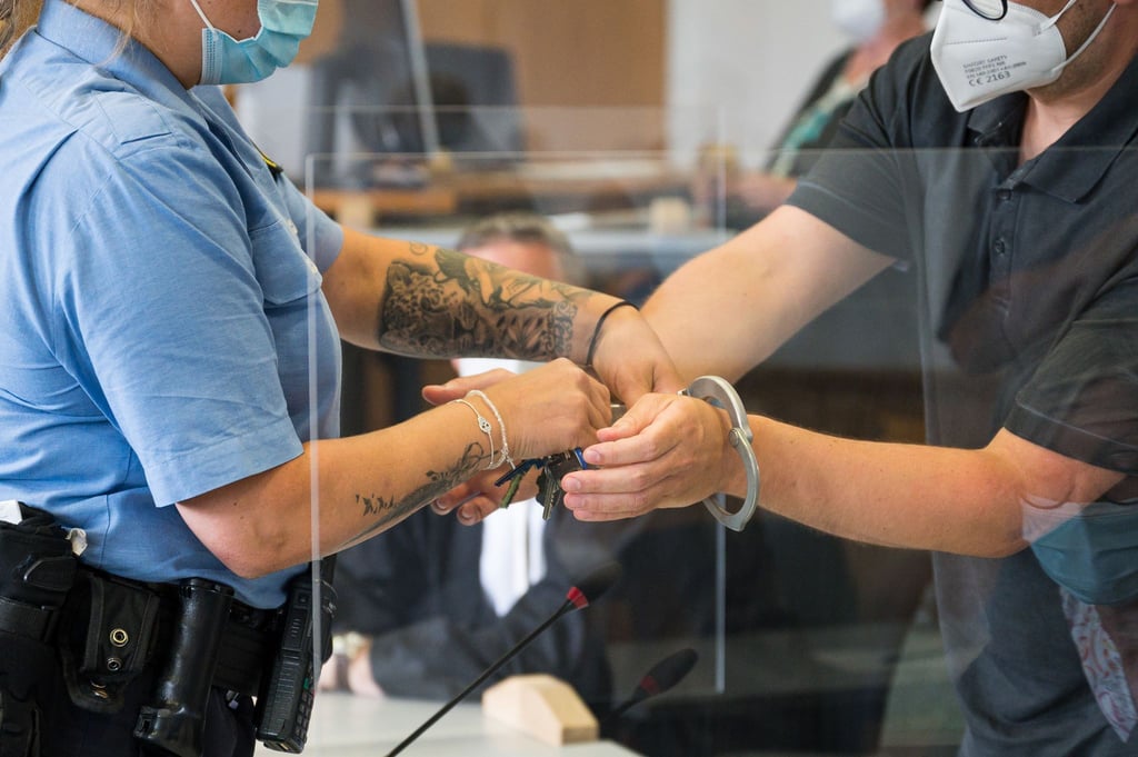 Eine Justizbeamtin (l) nimmt dem Angeklagten die Handschellen ab. Der 29-jährige Krankenpfleger muss sich wegen versuchten Mordes vor Gericht verantworten.