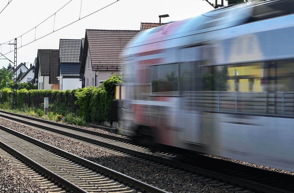 Auf der Bahnstrecke Karlsruhe-Mannheim fährt ein Zug an Häusern vorbei.