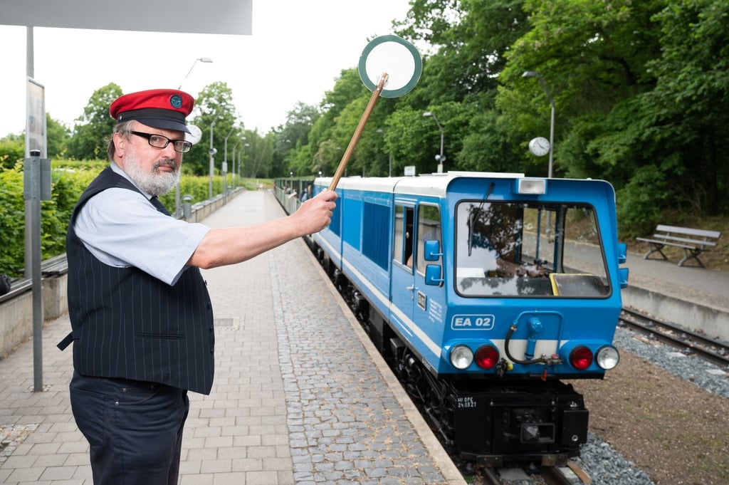 Uwe Schneider, Mitarbeiter der Parkeisenbahn Dresden, hebt am Hauptbahnhof die grüne Kelle zur Abfahrt.