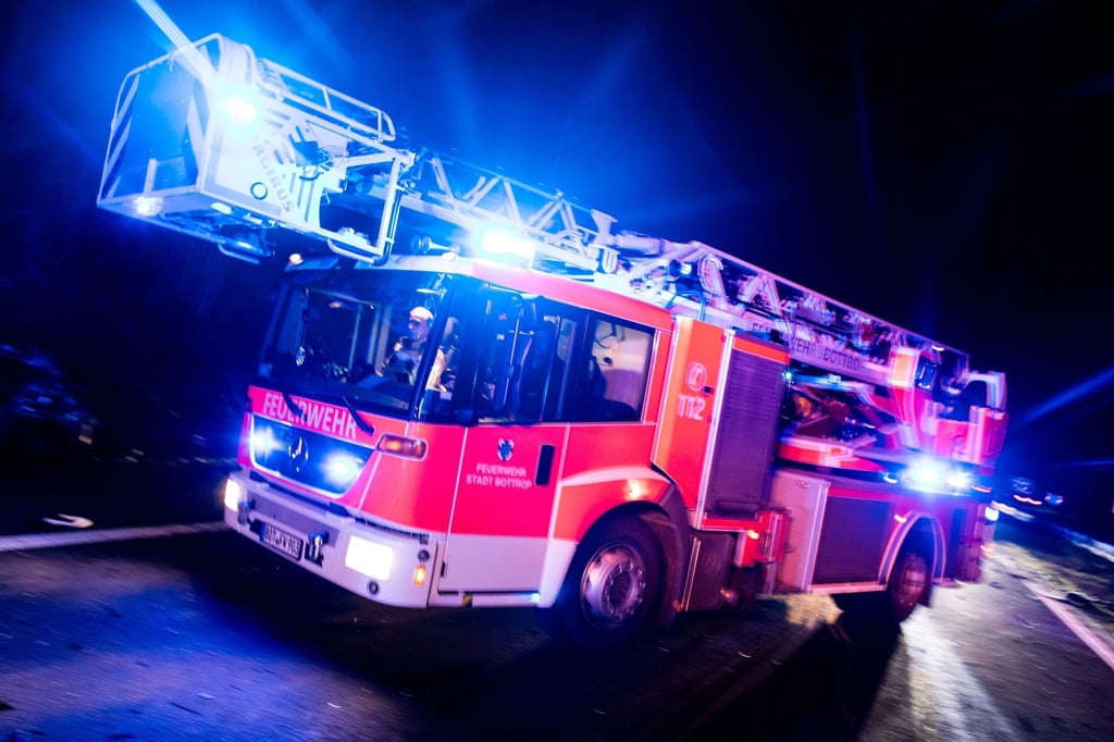 Ein Drehleiterwagen der Feuerwehr ist mit Blaulicht im Einsatz.
