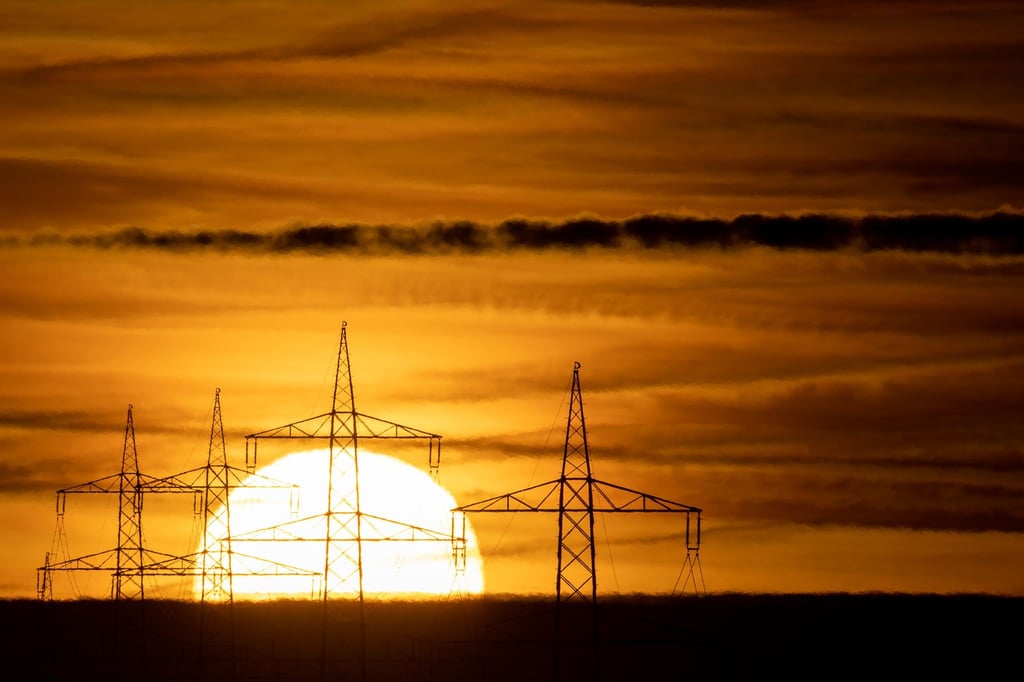 Die Sonne geht hinter Hochspannungsmasten auf (Symbolfoto).