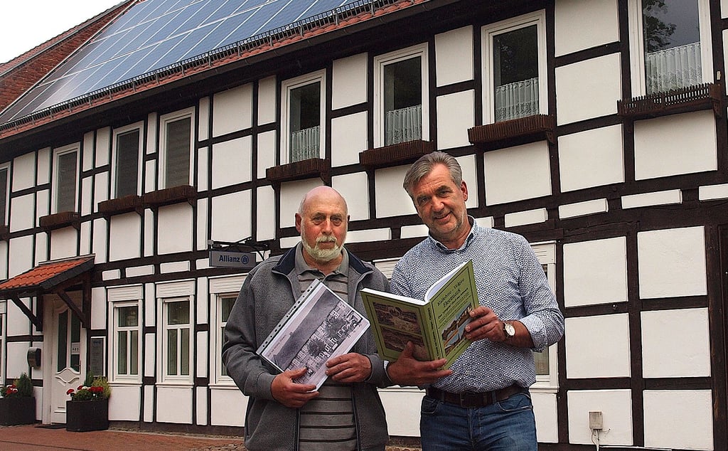 Friedrich-Wilhelm Schulz (links, mit einem Foto der 1919 errichteten Gaststätte Lemme) präsentiert die Chronik über Fleetmark mit Thomas Meyer vor dessen Geschäftssitz am Lindenpark.