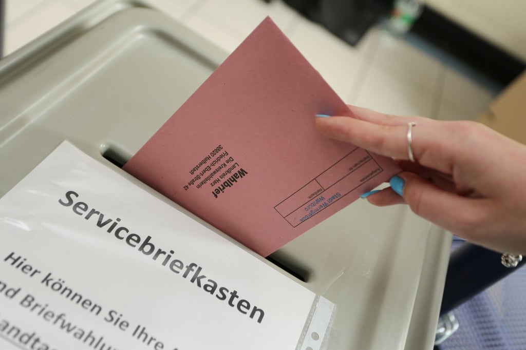 Briefwahlunterlagen werden in eine Wahlurne eingeworfen.