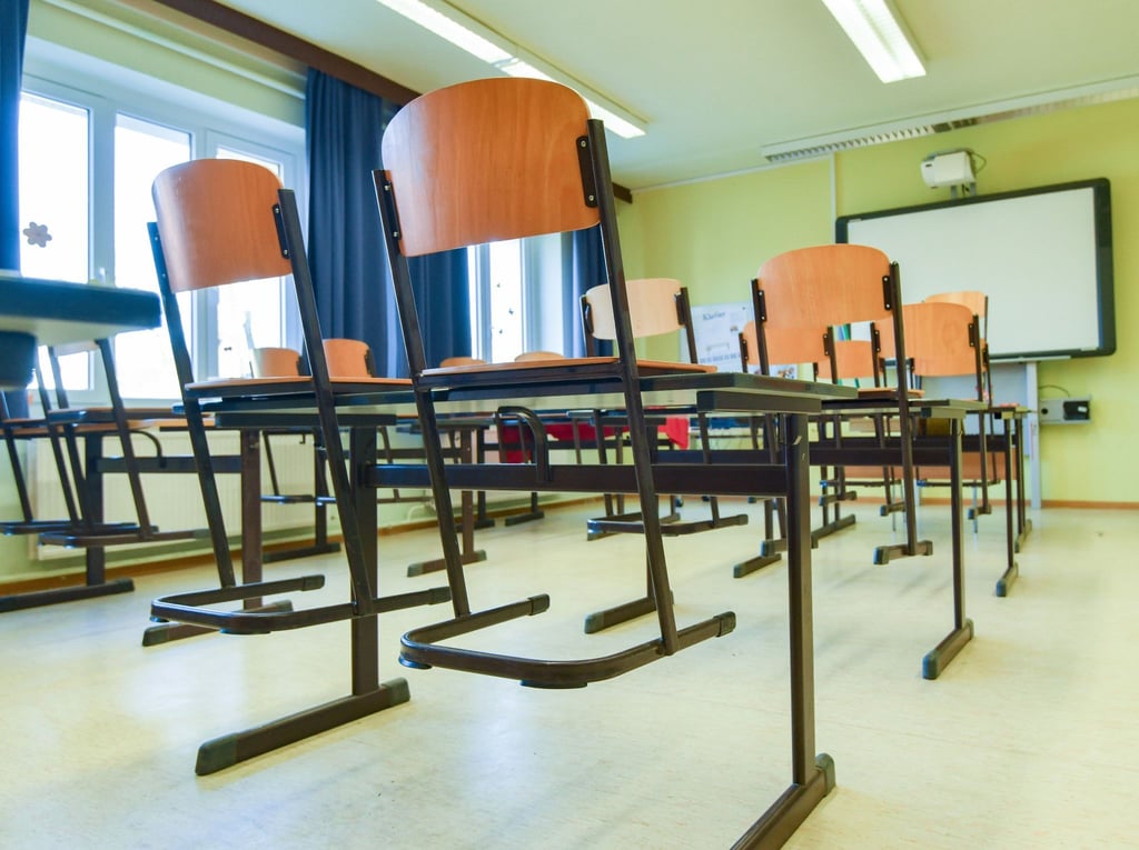 In einem leeren Unterrichtsraum an einer Grundschule stehen die Stühle auf den Tischen.