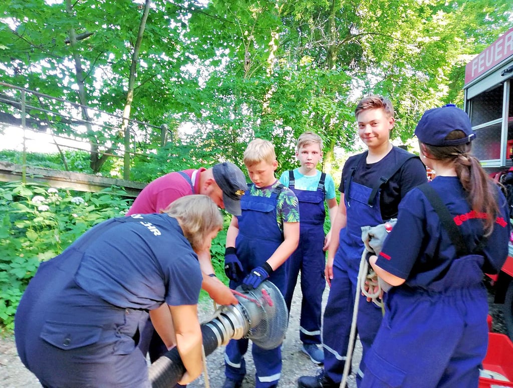 Elf Kinder zählt die Kinderfeuerwehr in Minkwitz. Gemeinsam mit Jugendwart René Oettel bauen sie eine Saugleitung in den Bach.
