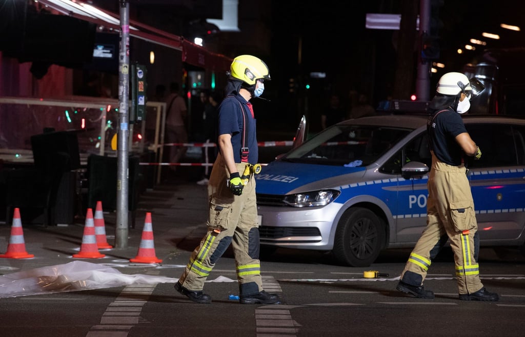 Feuerwehrleute gehen auf der Müllerstraße an Leitkegeln vorbei.