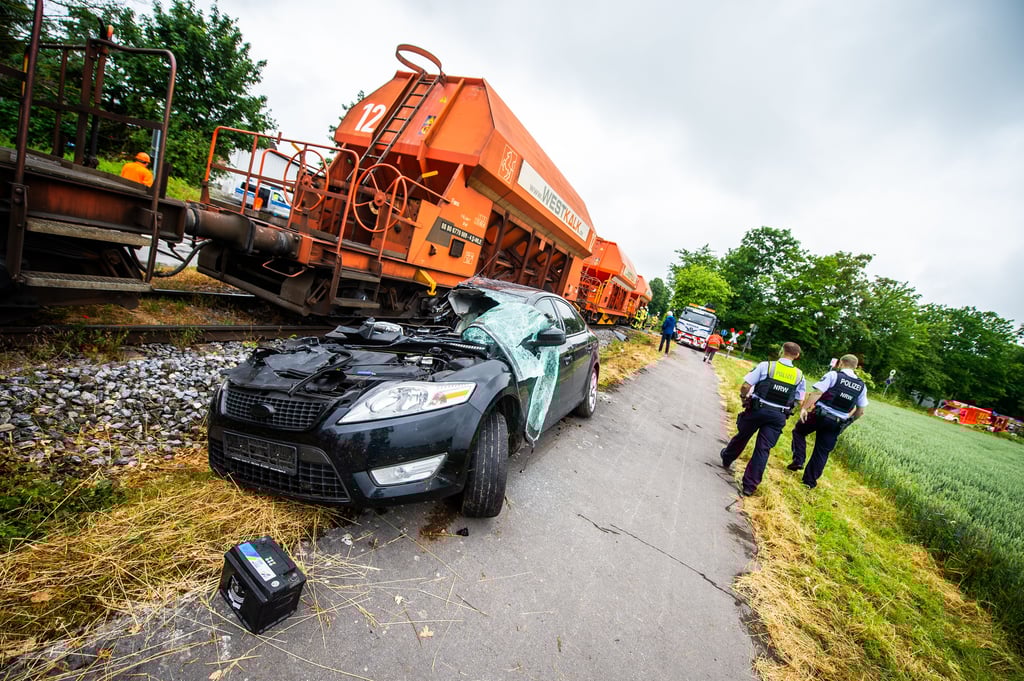 Ein beschädigtes Auto steht an den Gleisen neben einem Güterzug in Anröchte (Nordrhein-Westfalen). Ein Kind wurde hier schwer verletzt