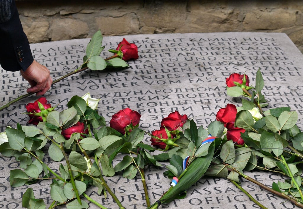Rote und weiße Rosen liegen auf einem Gedenkstein für über 8000 sowjetische Kriegsgefangene, die an dieser Stelle ermordet wurden, auf dem Gelände der KZ-Gedenkstätte Buchenwald.