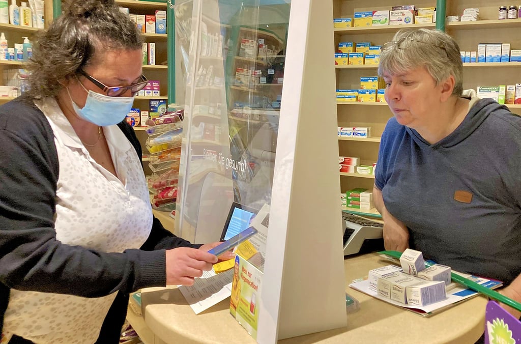 Apothekerin Elvira Zinn (rechts) erläutert ihren Kunden in der Apotheke im Vitalhaus in Quedlinburg, wie der digitale Impfnachweis funktioniert.
