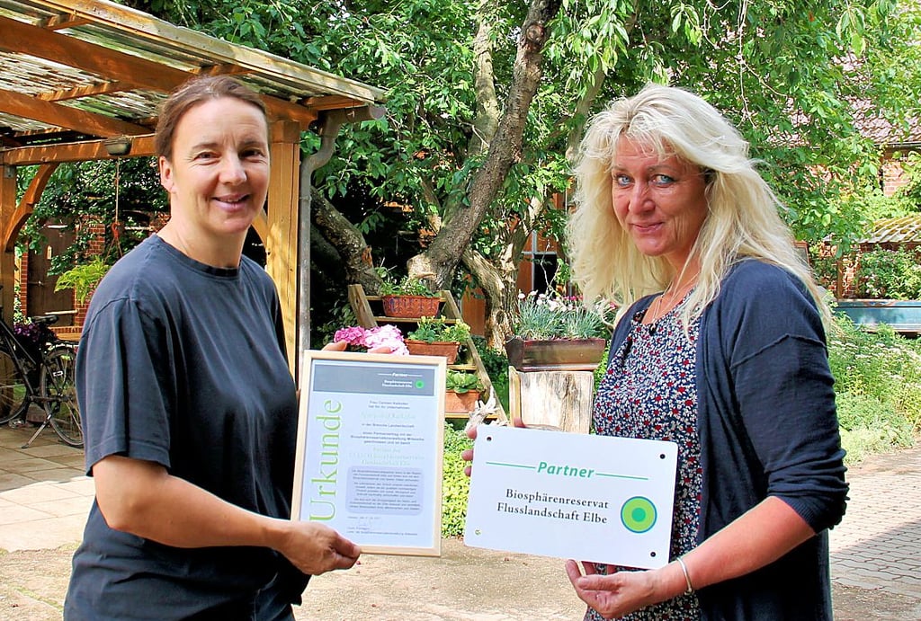 Carmen Kalkofen (links) erhält von Babett Wickler das Partnerschaft-Zertifikat und ein Schild für den Hof.