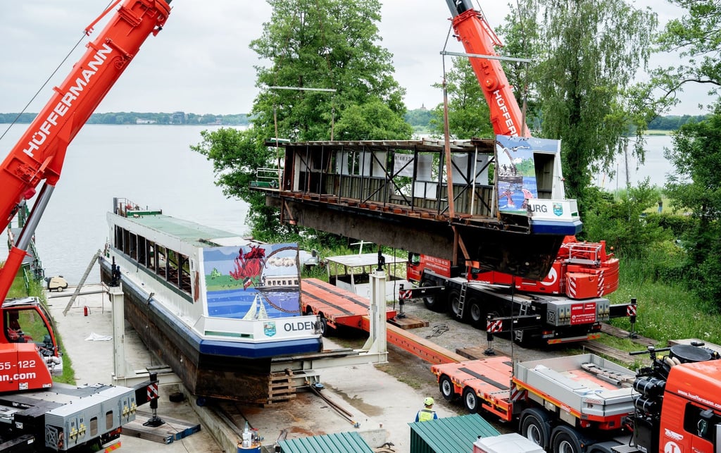 Zwei Mobilkrane heben ein Teilstück des längsseitig zersägten Fahrgastschiffes „MS Oldenburg“ am Zwischenahner Meer auf einen Tieflader.