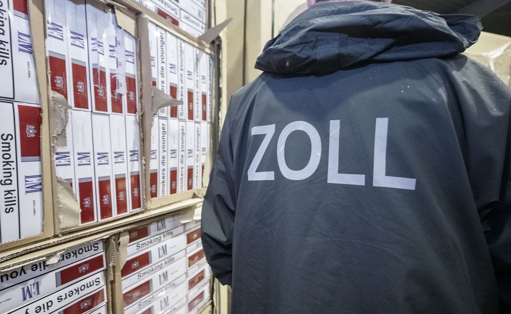 Ein Zollbeamter steht in einer Verwahrstelle des Zolls vor konfiszierten Paletten mit geschmuggelten Zigaretten.