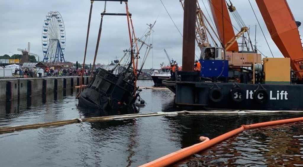 Ein Schwimmkran hebt den gesunkenen Kutter ?Wernigerode" am Montag aus dem Stadthafen Rostock. Die Feuerwehr hatte Ölschlängel rund um das Schiff verlegt.