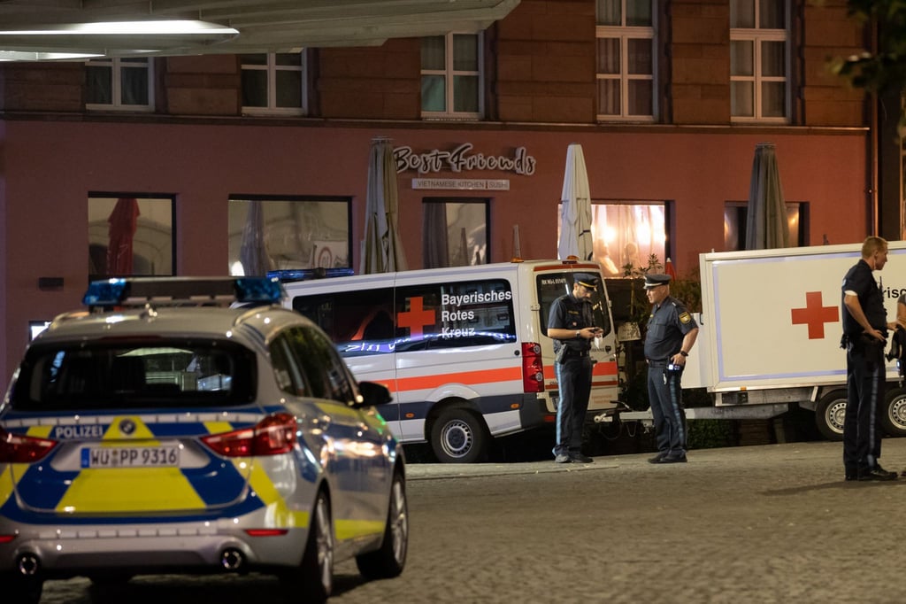 Einsatzfahrzeuge stehen nahe des Tatorts auf dem Barbarossaplatz in der Innenstadt von Würzburg.