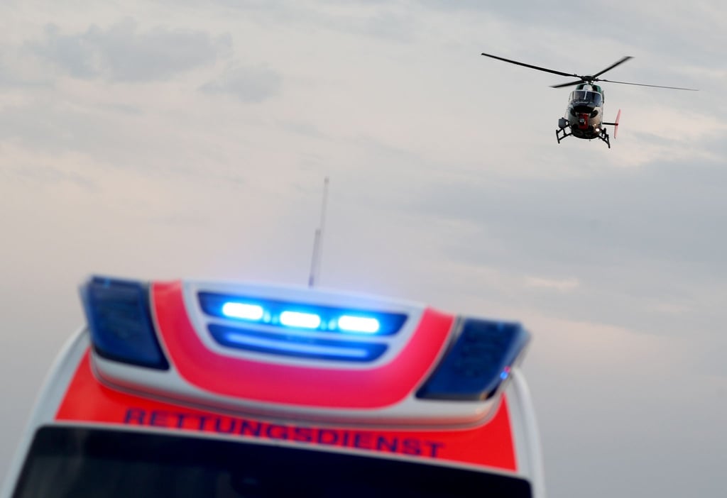 Ein Hubschrauber fliegt über einem Rettungswagen zu einem Unfallort.