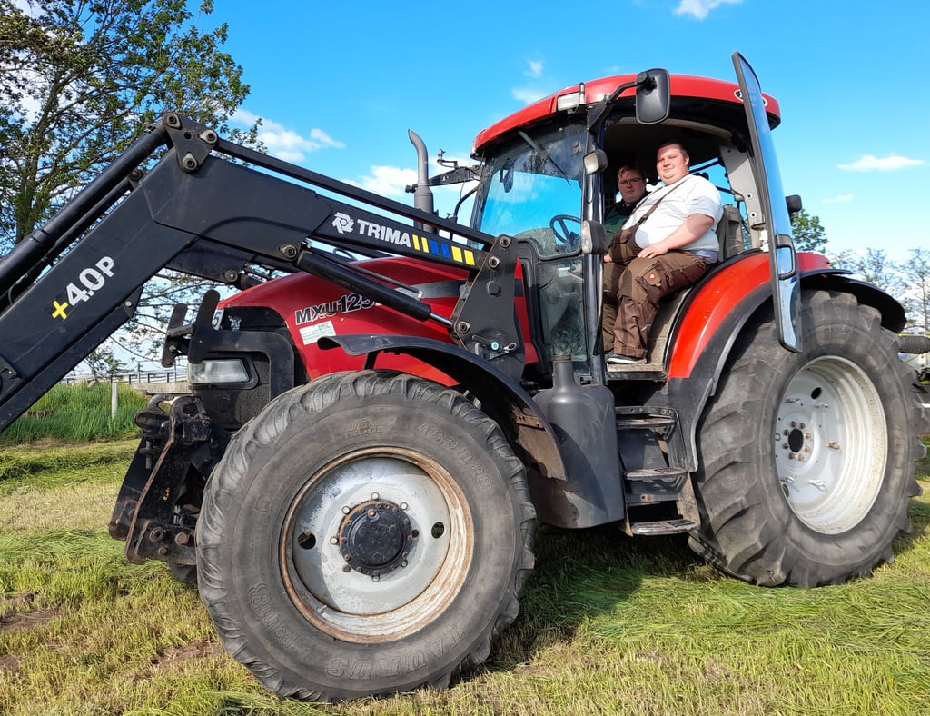 Landwirt Sebastian Scholz (vorn) zeigt auf einer Wiese bei Everingen dem Auszubildenden Benjamin Borth, wie mit Traktor und Schwadmäher das Grün geschnitten und auf den Boden gelegt wird. Gleich hinter der Technik finden Störche ihr Futter.