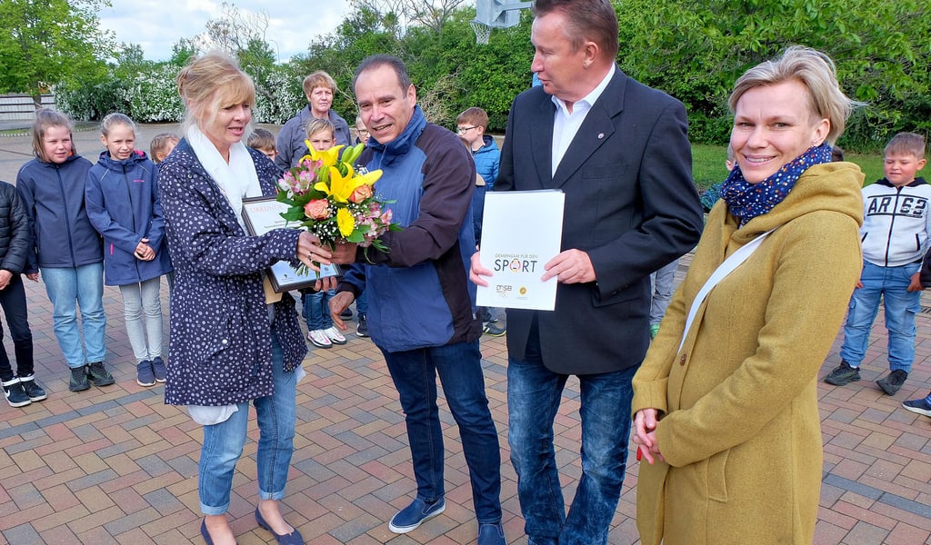 Kreissportbund-Präsident Uwe Loos überreicht der Leiterin der Grundschule Prettin, Sylvie Ebermann, die Urkunde und einen Blumenstrauß.