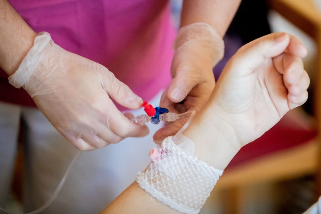 Eine Krankenpflegerin schließt bei einem Patientenrundgang eine Infusion an.