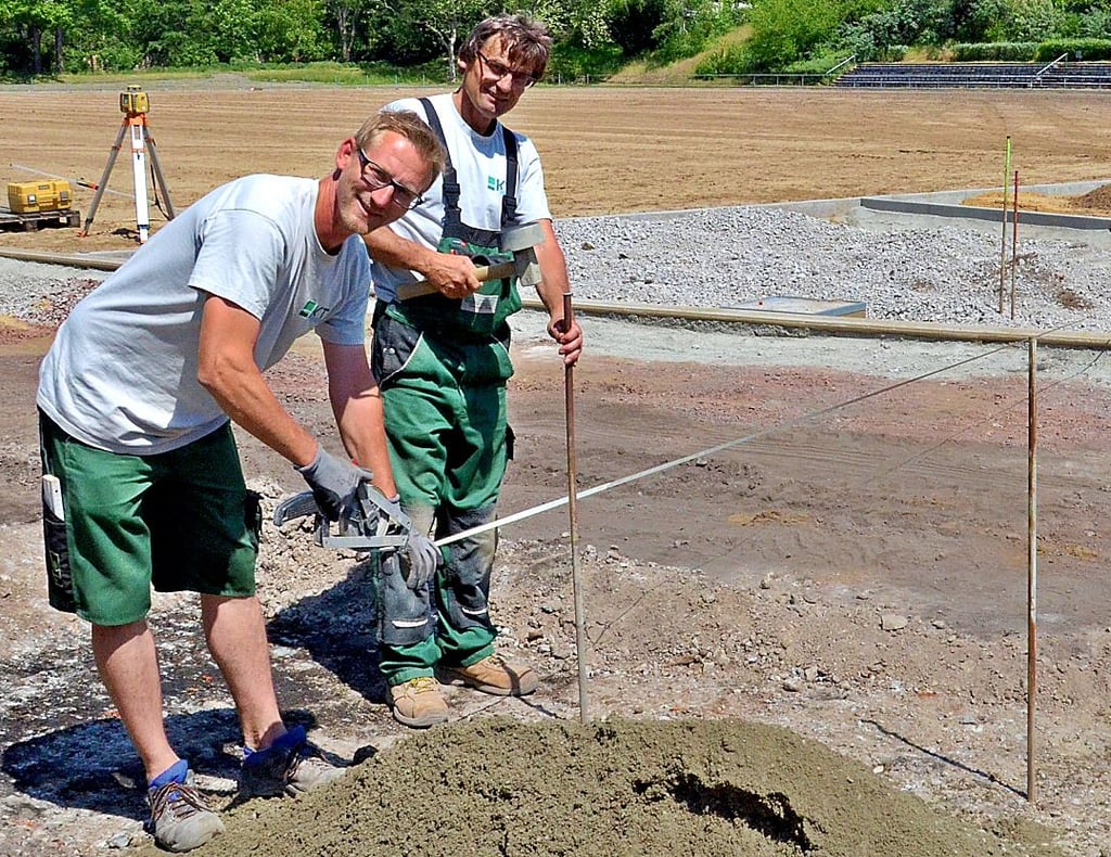 Christian Schäfer (l.) und Mario Rockmann von der Firma Keller+Tersch messen den Außenradius der Laufbahn im Zerbster-Jahn Stadion.