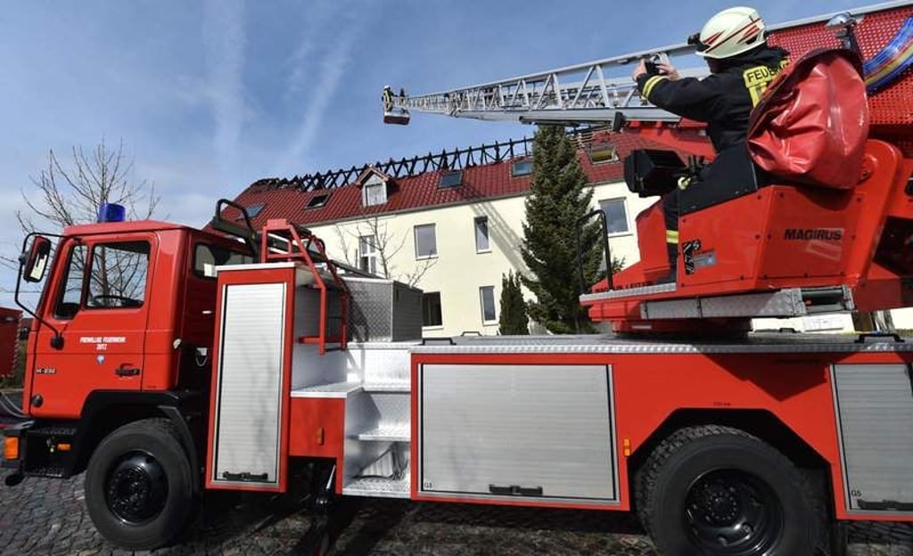 Einsatzkräfte von Feuerwehr und Polizei stehen am 04.04.2015 vor der zukünftigen Unterkunft für Asylbewerber in Tröglitz (Sachsen-Anhalt). In der Nacht hatte es in dem Gebäude gebrannt. Die Polizei ermittelt wegen Verdacht auf Brandstiftung. Foto: Hendrik Schmidt/dpa +++(c) dpa - Bildfunk+++