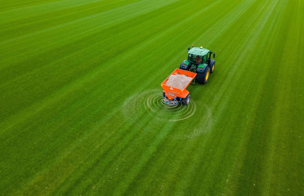 Zukünftiger Rollrasen für Fußballstadien wird auf einer Anbaufläche mit Sand bestreut.