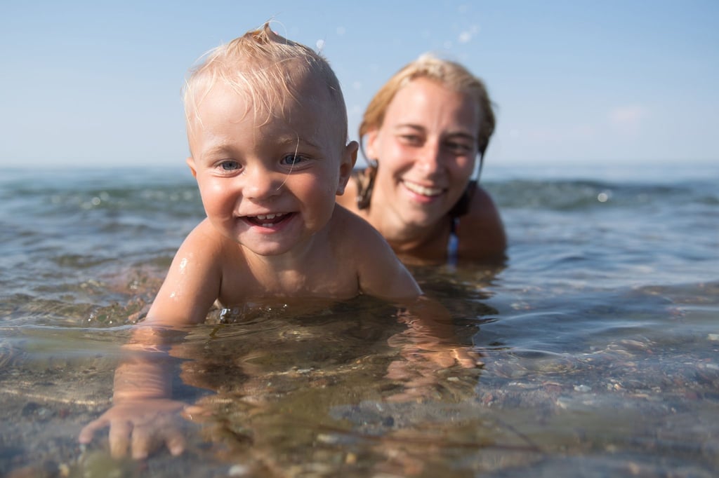 Ein kleiner Junge planscht vergnügt am Ufer. Seine Mama bleibt konsequent in Griffweite - so kann sie zupacken, falls etwas passiert.