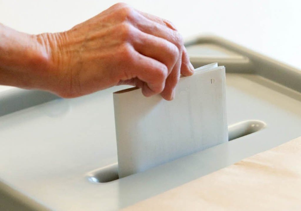 Eine Stimmzettel wird in die Wahlurne geworfen. (Symbolbild)