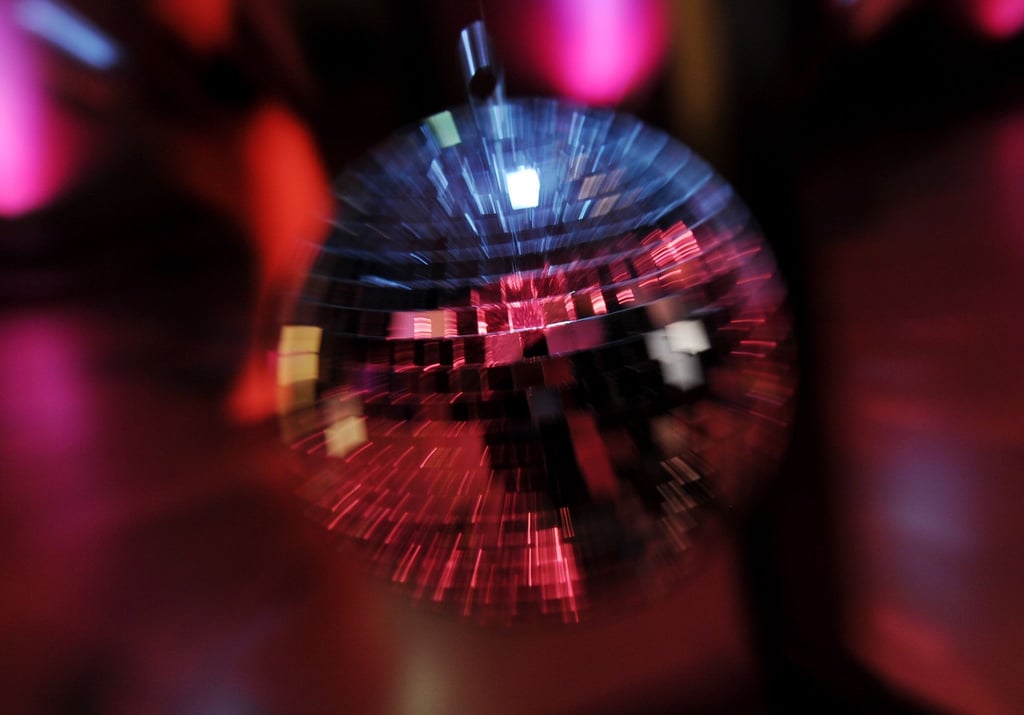 Scheinwerferlicht spiegelt sich in einer Discokugel.