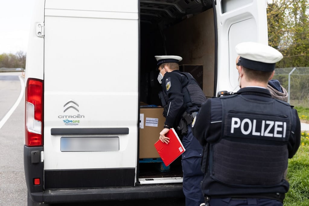 Bundespolizisten kontrollieren an einer Autobahn einen Transporter.