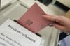 Briefwahlunterlagen werden in eine Wahlurne eingeworfen.