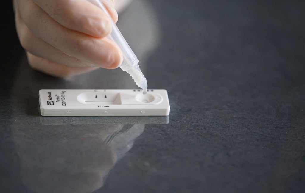 Eine Lösung wird auf eine Testkassette eines Corona-Schnelltests aufgeträufelt.