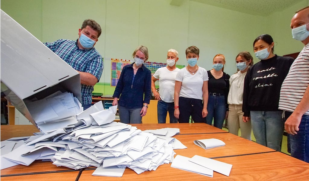 Nach Schließung des Wahllokals 2 in der Luisen-Grundschule schüttet Christian Grossy vor den Wahlhelfern die Stimmzettel auf die Tische.