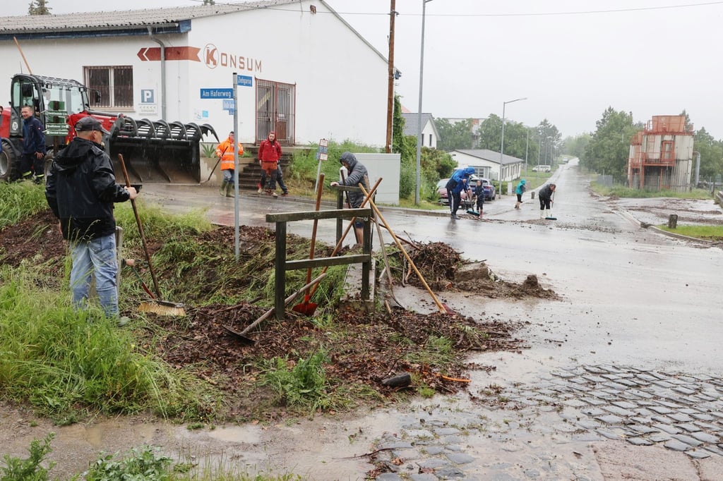 Helfer beseitigen Unrat aus einem Dorfbach nach heftigen Regenfällen am Sonntagmorgen.