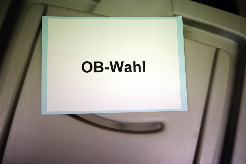Ein Zettel mit dem Schriftzug "OB-Wahl" liegt auf einer Wahlurne.