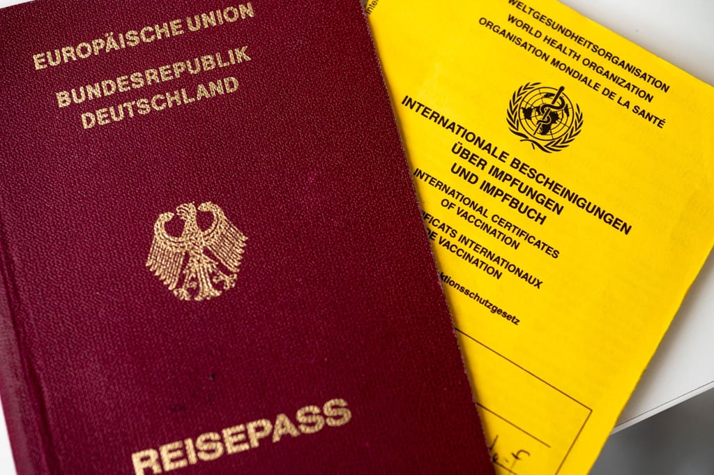 Ein deutscher Reisepass (l) liegt neben einem Impfbuch.