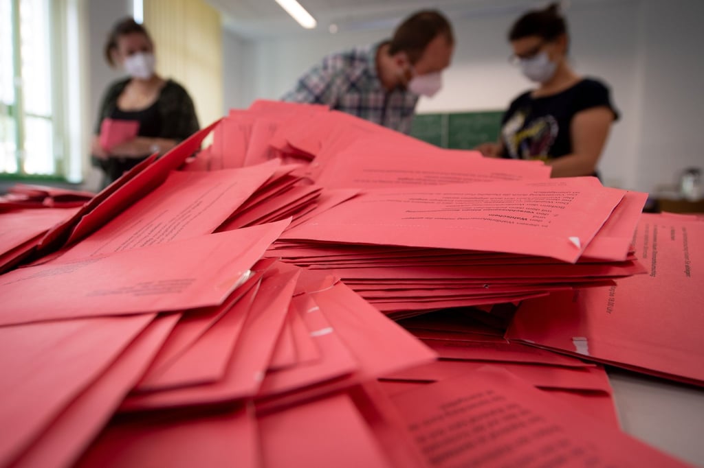 Wahlhelfer und Wahlhelferinnen öffnen im Klassenzimmer einer Schule in Magdeburg die Umschläge der Briefwahl.